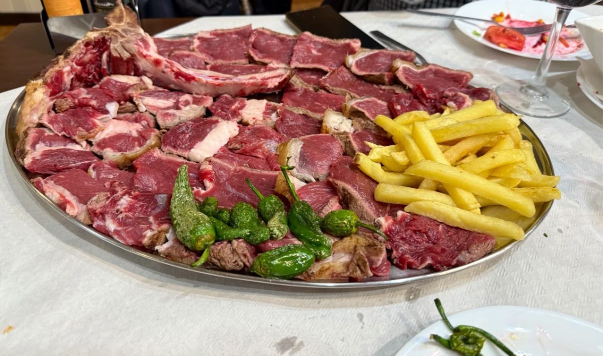 Fuente de chuletón de ternera cortado, con papas fritas y pimientos de Padrón