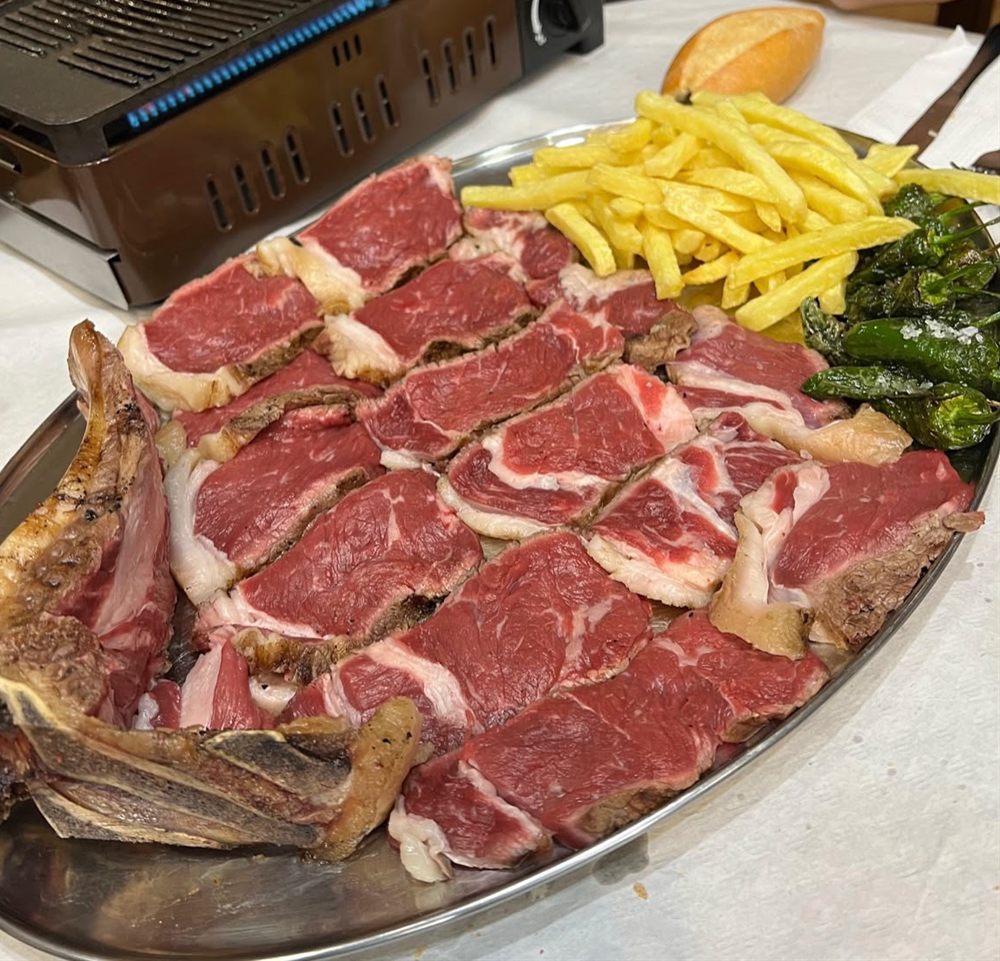 Chuletón cortado junto a una parrilla de mesa encendida