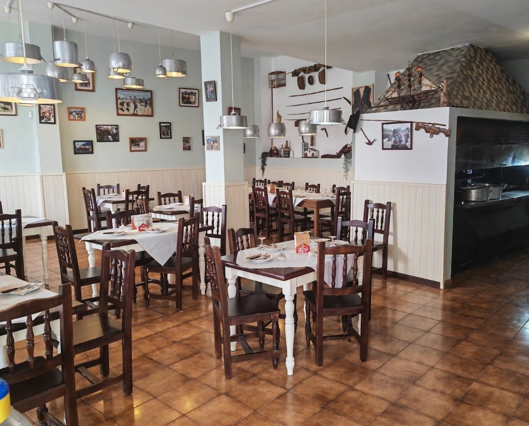 Comedor de El Guayero con mesas de madera y la brasa al fondo
